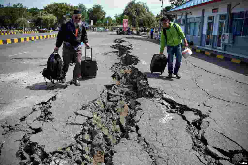 People walk on a road damaged by yesterday&#39;s large earthquake at Kayangan Port in Lombok, Indonesia, in this photo taken by Antara Foto.