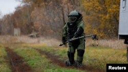 FILE - A Ukrainian service member, wearing protective gear, demonstrates using equipment to detect mines in a field, amid Russia's invasion, in the Kharkiv region of Ukraine, Oct. 27, 2022.