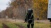 A Ukrainian service member, wearing protective gear, demonstrates using equipment to detect mines in a field in the Kharkiv region on October 27, 2022. (Clodagh Kilcoyne/Reuters)