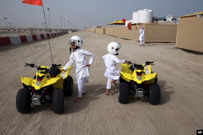 Dua bersaudara bersiap untuk naik dune buggies di sebuah kamp di Sealine Beach Road, sekitar 40 kilometer selatan Doha, Qatar, 19 April 2019. (AP/Kamran Jebreili)
