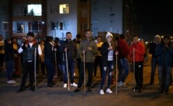 Residents hold sticks as they stand in front of their apartment block to guard their homes from possible looting after a curfew was enforced following renewed protests on the second day of a national strike, in Bogota, Colombia, Nov. 22, 2019.