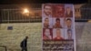 FILE - A man walks by a banner depicting the six Palestinian prison escapees, in the West Bank town of Bethlehem, September 8, 2021.