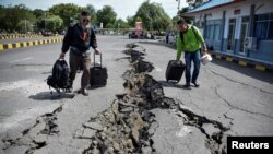 Warga berjalan di jalan yang rusak akibat gempa besar di Pelabuhan Kayangan, Lombok, 20 Agustus 2018. (Foto: dok). 