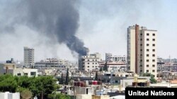 Smoke rises from buildings hit by shelling in Homs, Syria