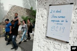 Cuban migrants line up to be called by Mexican immigration officials in Ciudad Juarez, Mexico, to be taken across the Paso del Norte International bridge to be processed as asylum-seekers on the U.S. side of the border, April 29, 2019. The sign on the wall reads in Spanish "April 28 The last number called in the afternoon is 8219."