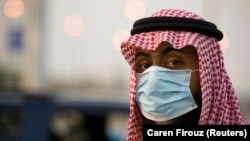 A security official wearing a protective mask keeps an eye on cars at a checkpoint between Jeddah and Mecca before the start of the annual Hajj pilgrimage November 21, 2009. 