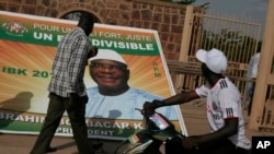 Passersby look at a poster supporting presidential candidate Ibrahim Boubacar Keita, with the slogan 'For a strong, just Mali, one and indivisible,' on the first day of campaigning, in Bamako, Mali, July 7, 2013.