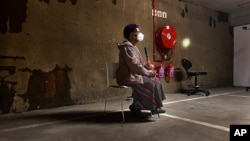 A lone woman waits to be tested for COVID-19 in the parking garage of a shopping mall in Johannesburg, South Africa, Monday Jan. 11, 2021. (VOA)