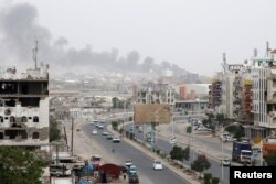 Smoke billows from a car parts store hit by shelling during the conflict in the port city of Aden, Yemen Jan. 31, 2018.