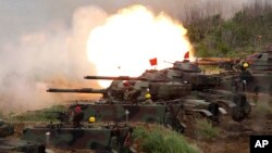 FILE- In this May 25, 2017, file photo, a line of U.S. M60A3 Patton tank fire at targets during the annual Han Kuang exercises on the outlying Penghu Island, Taiwan.
