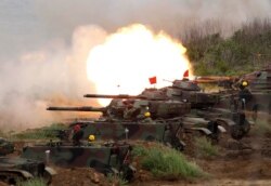 FILE- In this May 25, 2017, file photo, a line of U.S. M60A3 Patton tank fire at targets during the annual Han Kuang exercises on the outlying Penghu Island, Taiwan.