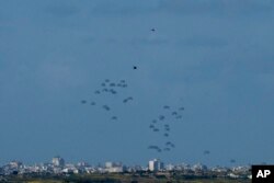 FILE —Parachutes drop supplies into the northern Gaza Strip, as seen from southern Israel, March 7, 2024.