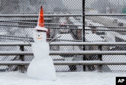 A snowman wearing a traffic cone hat is shown on an overpass as early morning traffic is at a standstill in the background on Interstate 5 headed into Portland, Oregon, Jan. 11, 2017.