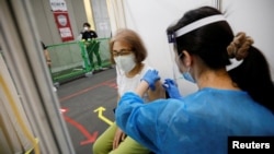 A woman receives a dose of the COVID-19 vaccine at the Noevir Stadium Kobe, the home venue of Japanese professional soccer club Vissel Kobe and currently acting as a large-scale COVID-19 vaccination center, in Kobe, Japan, June 12, 2021.
