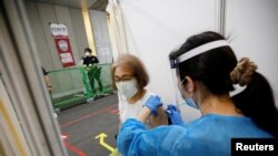 A woman receives a dose of the COVID-19 vaccine at the Noevir Stadium Kobe, the home venue of Japanese professional soccer club Vissel Kobe and currently acting as a large-scale COVID-19 vaccination center, in Kobe, Japan, June 12, 2021.