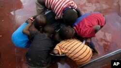 Kids scrape for remaining rice inside a pot at a displacement center in Beira, Mozambique, March 22, 2019. 