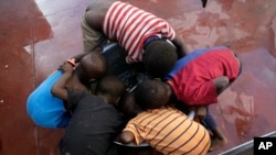 Des enfants raclent les restes de leur riz dans un pot dans un centre de déplacement à Beira, au Mozambique, le 22 mars 2019.