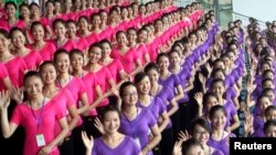 Volunteers, who will be hostesses of Nanjing 2014 Youth Olympic Games, smile and wave during a training in Nanjing, Jiangsu province.