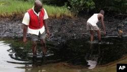 Men walk in an oil slick covering a creek near Bodo City in the oil-rich Niger Delta region of Nigeria. File