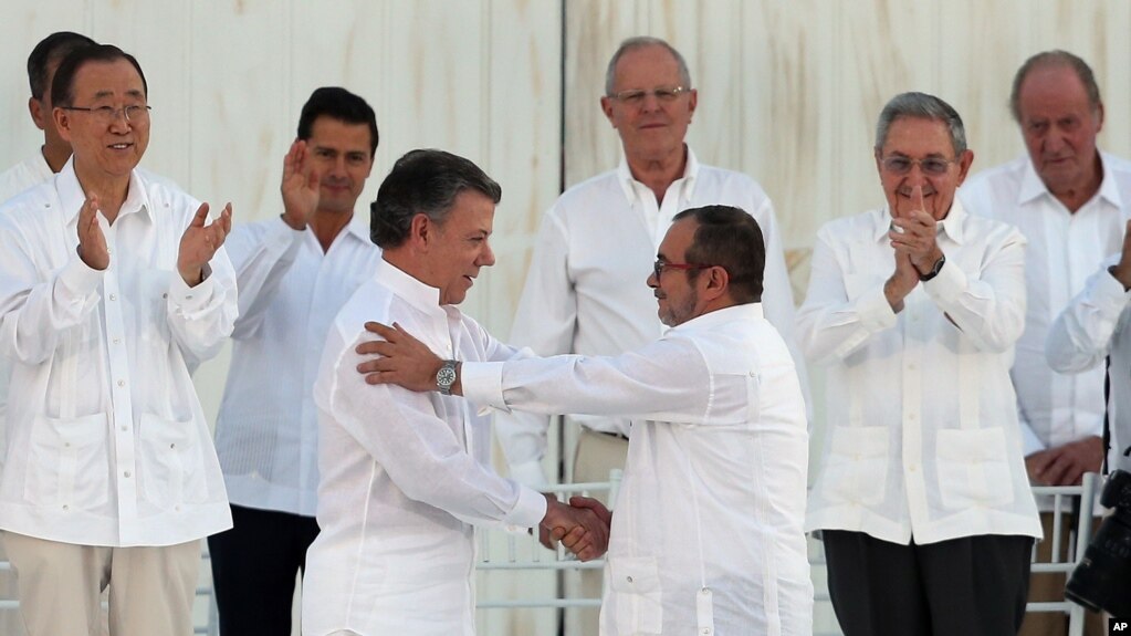 Colombia’s President Juan Manuel Santos, front left, and the top commander of the Revolutionary Armed Forces of Colombia (FARC) Rodrigo Londono, known as Timochenko, shake hands after signing a peace agreement in Cartagena, September 26, 2016. The agreement ends more than 50 years of conflict between Colombia’s government and the FARC. Behind, from left, are U.N. Secretary General Ban Ki Moon, Mexico's President Enrique Pena Nieto, Peru's President Pedro Pablo Kuczynski, Cuba's President Raul Castro, and Spain's former King Juan Carlos. (AP Photo/Fernando Vergara)