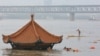 在被洪水淹没的武汉长江旁的一个只露出顶部的亭子边有武汉民众在游泳。（2020年7月8日）