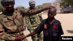 A Chadian soldier embraces a former child soldier of insurgent group Boko Haram in Ngouboua, Chad, April 22, 2015. The young men said they were Chadian nationals forced to join Boko Haram while studying the Quran in Nigeria, and that they escaped and turned themselves in to Chadian authorities. (REUTERS/Moumine Ngarmbassa)