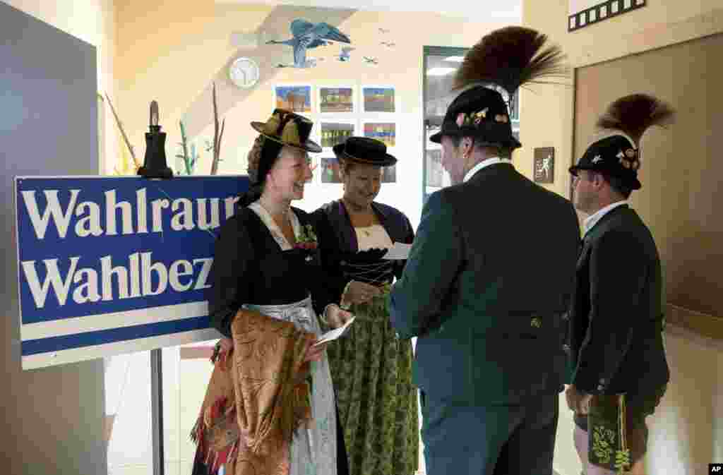 Women and men in traditional Bavarian costumes stand at a polling station before casting their vote in Unterwoessen, southern Germany, Sept. 24, 2017.