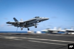 FILE - An F/A-18E Super Hornet lands on the flight deck of the Nimitz-class aircraft carrier USS Abraham Lincoln in the Arabian Sea, May 20, 2019.