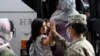 FILE - In this Aug. 30, 2021, photo, Army Pfc. Kimberly Hernandez gives a high-five to a girl evacuated from Kabul, before boarding a bus after they arrived at Washington Dulles International Airport.