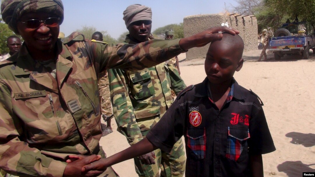 FILE - A Chadian soldier embraces a former child soldier of insurgent group Boko Haram in Ngouboua, Chad, April 22, 2015. An 11-year-old boy arrested by soldiers says Boko Haram trained him as a suicide bomber and his mission was to blow himself up among refugees in a northeast Nigerian camp.