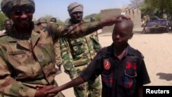 FILE - A Chadian soldier embraces a former child soldier of insurgent group Boko Haram in Ngouboua, Chad, April 22, 2015. An 11-year-old boy arrested by soldiers says Boko Haram trained him as a suicide bomber and his mission was to blow himself up among refugees in a northeast Nigerian camp.