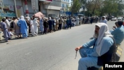 FILE - Afghans line up outside a bank to take out their money after Taliban takeover in Kabul, Afghanistan, Sept. 1, 2021. 