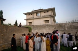FILE - In this May 3, 2011, photo, local residents gather outside a compound where al-Qaida leader Osama bin Laden was killed by U.S. forces, in Abbottabad, Pakistan.