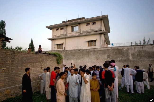 FILE - In this May 3, 2011, photo, local residents gather outside a compound where al-Qaida leader Osama bin Laden was killed by U.S. forces, in Abbottabad, Pakistan.
