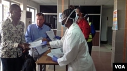 Staff hand out health forms to arriving passengers, Lungi international airport, Sierra Leone, Feb. 3, 2015. (Nina deVries/ VOA)