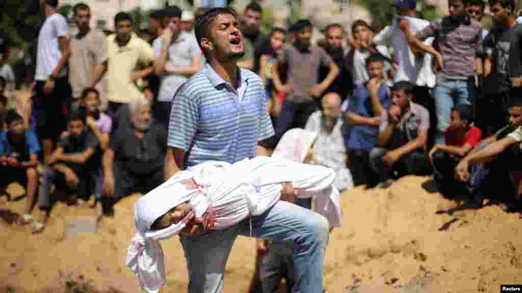A Palestinian man carries the body of a girl from the Abu Nejim family, whom medics said was killed along with other eight family members by an Israeli air strike in the northern Gaza Strip, August 4, 2014.
