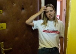 Wartawan Rusia Maria Zholobova berdiri di samping pintu apartemennya di Moskow, Rusia, setelah penggeledahan, Selasa, 29 Juni 2021. (AP)