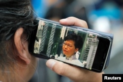 Carrie Lam'in basın toplantısını cep telefonundan izleyen bir Hong Konglu