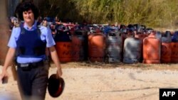 A policewoman walks with dozen of gas bottles in background in Alcanar during a search linked to the Barcelona and Cambrils attacks on the site of an explosion on August 18, 2017.