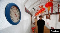 A waiter stands next to a thermometer indicating -10 degree reading during a photo opportunity at the Ice Palace in Shangri-La Hotel in the northern city of Harbin, Heilongjiang province January 6, 2014. The Ice Palace, which is built by ice bricks, is op