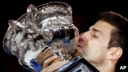 Novak Djokovic of Serbia kisses the trophy after defeating Andy Murray of Britain in during the men's singles final at the Australian Open tennis championship in Melbourne, Feb. 1, 2015.