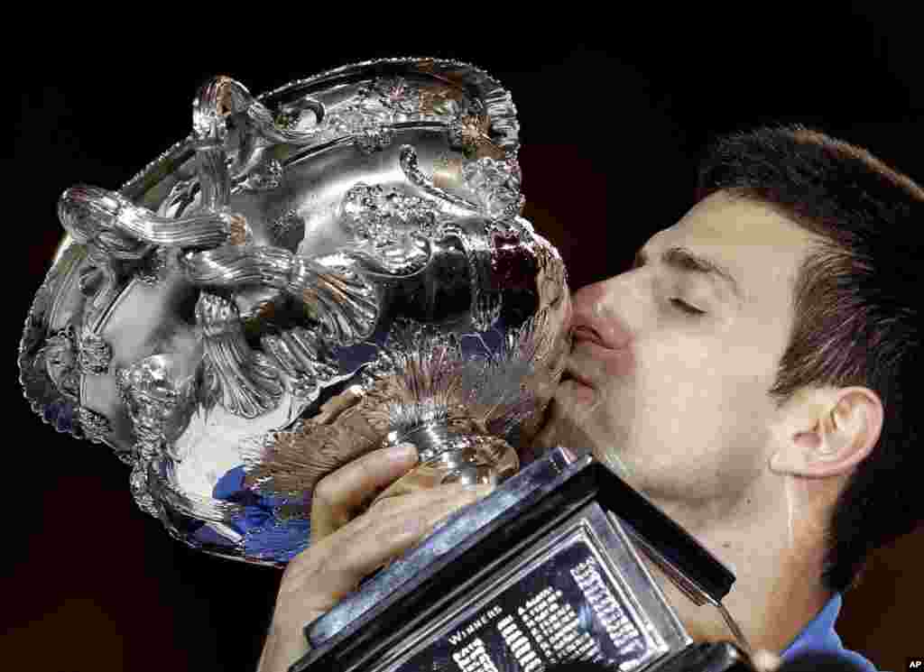 Novak Djokovic of Serbia kisses the trophy after defeating Andy Murray of Britain during the men&#39;s singles final at the Australian Open tennis championship in Melbourne.