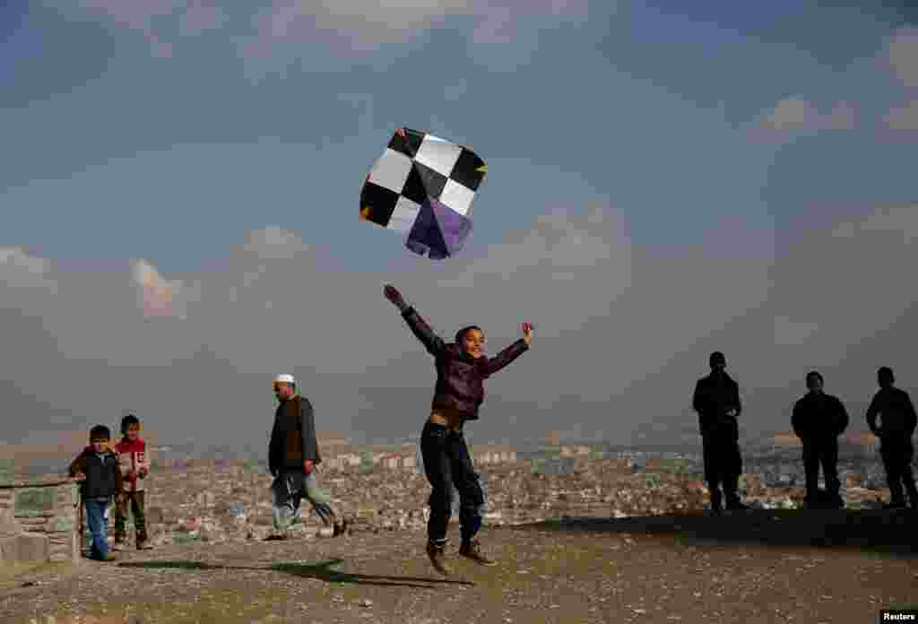 An Afghan boy launches a kite on top of a hill in Kabul.