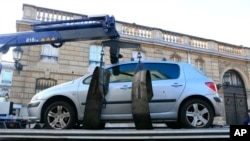 Car is towed away after its driver tried to ram through a gate of the presidential Elysee Palace, visible in background, Paris, Dec. 26, 2013.