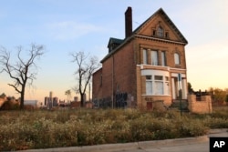 FILE - A photo shows a graffiti-marked abandoned home north of downtown Detroit, in the background, Oct. 24, 2013.