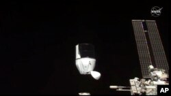 资料照片:NASA提供的照片显示太空探索龙飞船正在脱离国际空间站。(2021年1月12日)