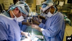 El Dr. Sunil Singhal, derecha, maneja una cámara especial que le permite ver tumores en un monitor mientras realiza una cirugía en el Hospital de la Universidad de Pennsylvania en Philadelphia. Enero 23, 2018.
