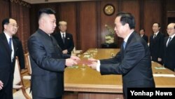 지난해 11월 중국 공산당 대표단으로부터 시진핑 공산당 총서기의 친서를 전달받은 김정은 북한 국방위원회 제1위원장(왼쪽). (자료사진)