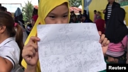 An evacuated student shows her drawing about what she and other Marawi residents experienced before fleeing the city still under siege during a school day at Pantar elementary school in Lanao Del Norte, Philippines, June 6, 2017.