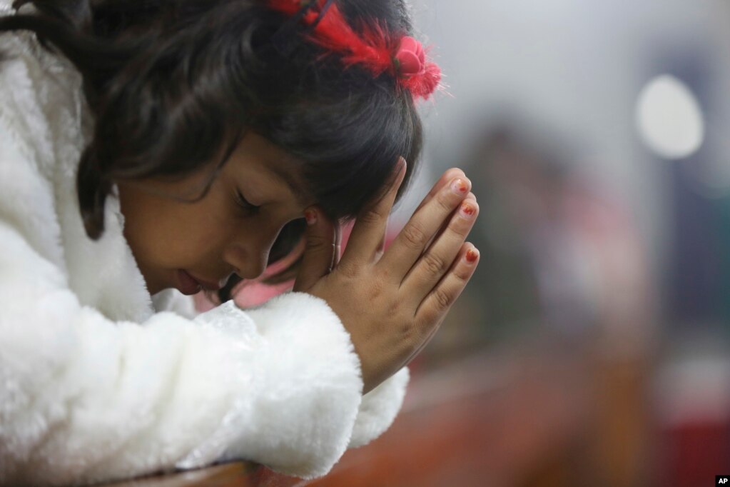 An Indian girl prays during the midnight Christmas Mass at Saint Joseph's Cathedral in Lucknow, India, Dec. 25, 2017.